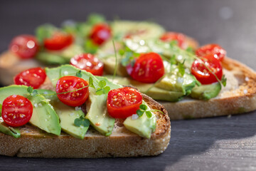 A slice of toasted sour dough bread with avocado and tomato on top
