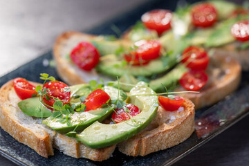 A slice of toasted sour dough bread with avocado and tomato on top