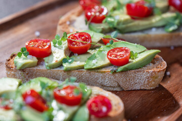 A slice of toasted sour dough bread with avocado and tomato on top