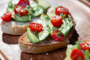 A slice of toasted sour dough bread with avocado and tomato on top