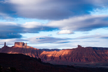 Stunning sunrise over red rock butte formations near Moab, Utah. The breathtaking landscape is illuminated by the morning light and dramatic sky, creating an awe-inspiring natural scene - USA