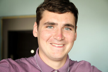 Portrait of happy young man. 20s smiling man. Closeup portrait. Man with blue or grey eyes. Crooked teeth. Candid young man