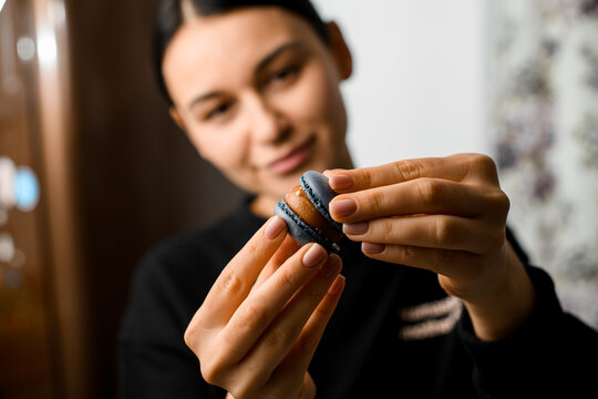 Smiling young girl makes appetizing gray blue macaron with a whipped creamy
