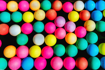Top view of many colorful plastic balls on water. View of colored sponge balls. Many colorful balls as background. Lots of colorful balls for children to play in the water park. Toy pool for kids.