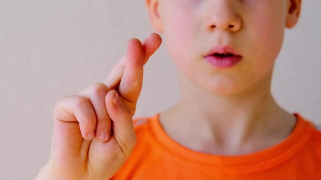 Close-up of child's crossed fingers for luck, 9-year-old boy making motivational gesture symbolizing hope, support, optimism concept emotional development, encouraging gestures, childhood optimism
