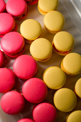 Dark pink and yellow appetizing tasty macarons in glass bowl
