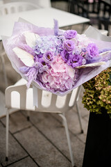 Purple and pink charming flowers in a bouquet on a chair on the street