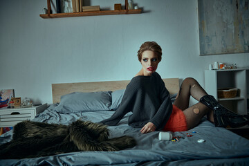 A woman in stylish clothing poses on a bed with a fur throw.