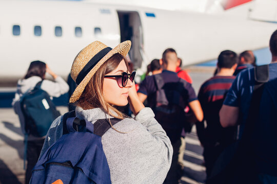 Woman traveler boarding on plane standing in line. Passenger with backpack standing in queue ready for flight