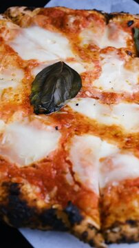 Close-up, Margherita pizza with melted mozzarella cheese spinning in a circle. Vertical video. Fresh delicious food. Pizza Margherita. Italian Cuisine.