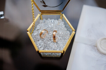 A gold and white wedding ring box with two rings inside