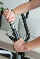 Male hands on a home exercise machine, home sports concept.