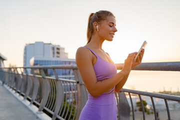 attractive young woman doing sports in the morning using smartphone