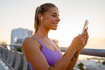 attractive young woman doing sports in the morning using smartphone