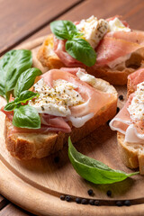 Deliziose bruschette condite con mozzarella di bufala e prosciutto crudo, spuntino italiano 