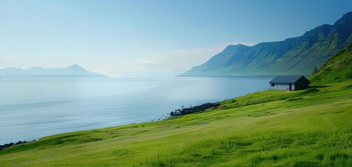A small cabin sits on a grassy hill overlooking a body of water
