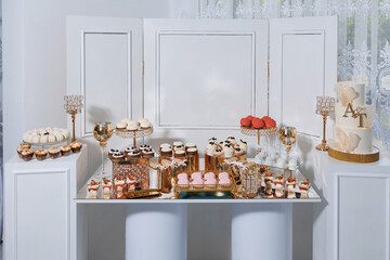 A table with a variety of desserts and a cake with the letters A and T on it. The table is set up for a special occasion, possibly a wedding or a birthday party