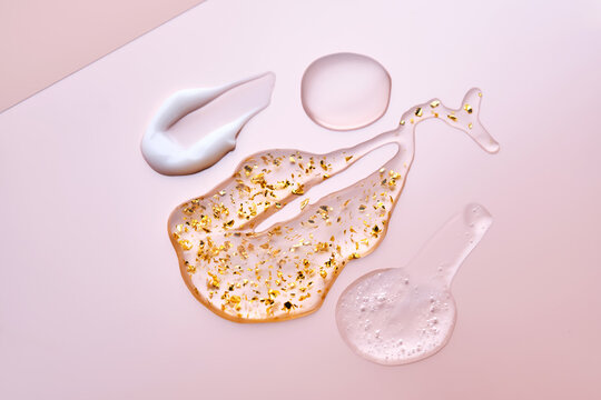 Texture of face serum, cream, oil and serum with 24k gold on a pink background.