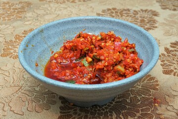 Indonesian red chili sauce in a bowl on a dining table with indoor lighting