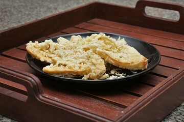 Crispy fried banana. typical Indonesian snack, photographed on a black plate on a table with indoor lighting