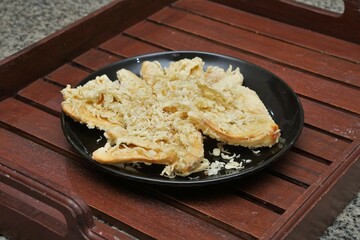 Crispy fried banana. typical Indonesian snack, photographed on a black plate on a table with indoor lighting