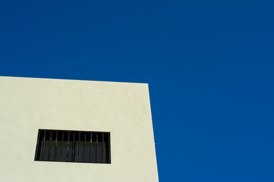 fondo arquitect&oacute;nico del edificio con cielo azul, con ventanas negras y forma geom&eacute;trica