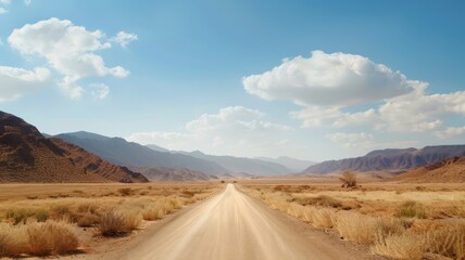 Fototapeta premium A road stretching through a vast desert landscape with mountains in the distance under a clear blue sky