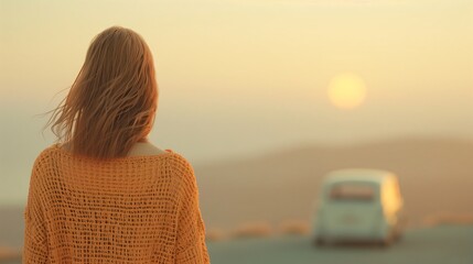 Fototapeta premium Woman enjoys a peaceful sunset by her vintage car on an empty road, feeling free and happy in nature's beauty