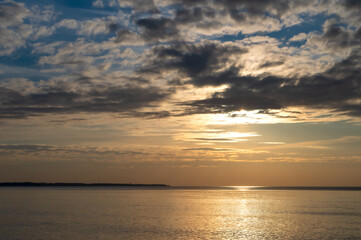 Fototapeta premium Sunset over the sea. Reflection of sunlight in the sea waves. The sky in the sunset rays. Baltic Sea.