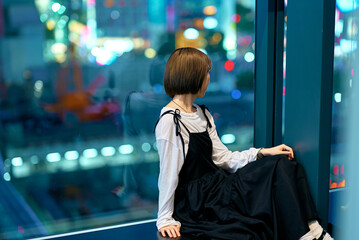 夜の繁華街を見つめる若い女性