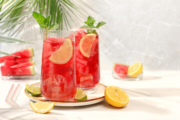 Ice cold homemade lemonade or cocktail with mint, watermelon and fruits on a sunny table, refreshing summer drink recipe, detox diet and weight loss concept, menu for restaurant, selective focus..