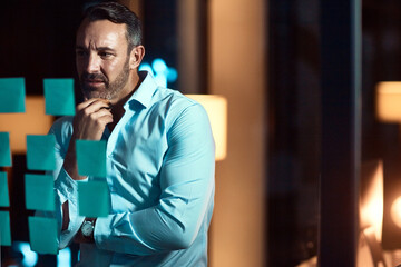 Night, thinking and business man with glass board for strategy, project ideas or brainstorming in...