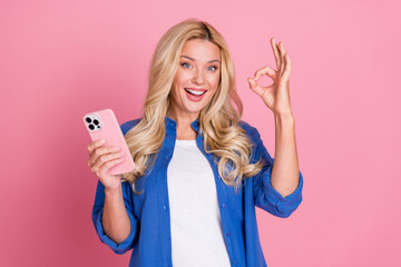 Photo of shiny attractive lady dressed blue jacket communicating modern device showing okey sign isolated pink color background