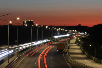 View of streaks of light from cars against a red sunset background