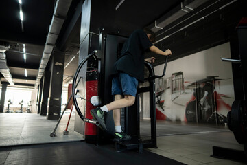 man works out on a leg press machine in a gym, using his legs to push a weight platform