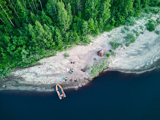 An orange boat on the riverbank. Sandy beach. Bird's eye view of beautiful forest with river.