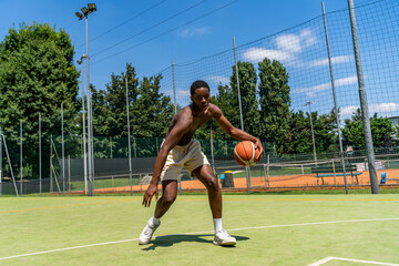 Fototapeta premium young african american athlete basketball player in action dribbling on artificial grass playing field on a sunny summer day outdoors