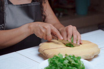 Hands of a cook with a knife cutting fresh lettuce leaves.