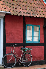 Bike parked in front of  dark red half-timbered house on the island Bornholm, Denmark.
