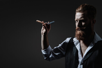 Modern barbershop haircut. Bearded hipster barber isolated on black. Man beard haircut by hairdresser at barbershop. Handsome barber using retro blade while cutting hair. Barber razor