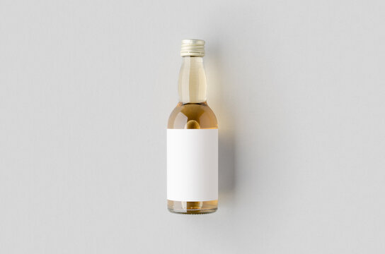 Miniature spirits, liquor bottle mockup. Clear glass, amber liquid with a blank label.
