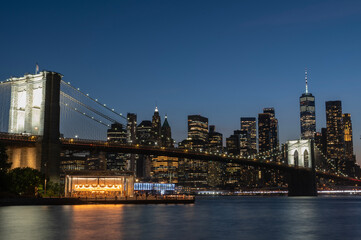 Night time view of New York Manhattan and Brooklyn Bridge with sea