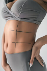 Middle part of woman's body with contour lines for cosmetic surgery on gray background