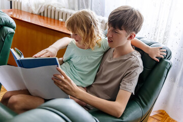 Obraz premium Brother and Sister Reading a Book Together in a Living Room