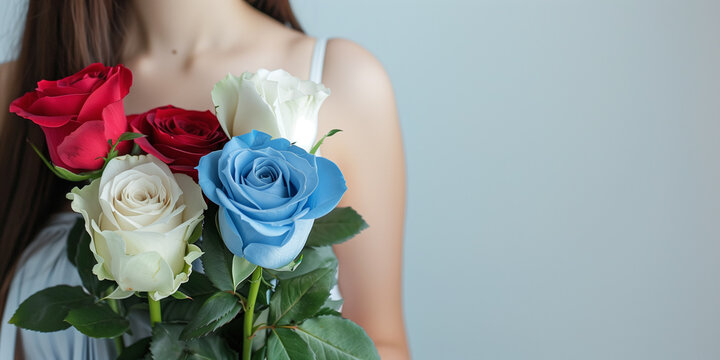 A woman holds a bouquet of blue, white, and red roses