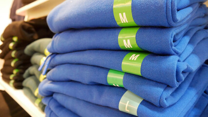 Close-up of many folded clothes sorted by size and color in a clothing store