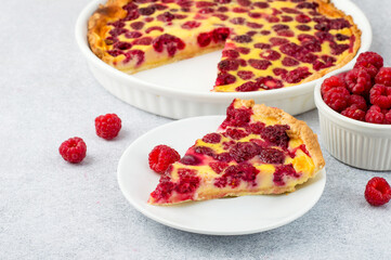 A piece of raspberry pie on a plate and a whole pie in a ceramic form. Seasonal summer baking. Horizontal, free copy space.