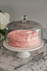 Strawberry pink homemade cake on a marble counter with cake knife, verticle, close-up