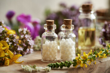 Homeopathic pills or globules in two glass bottles with various summer flowers