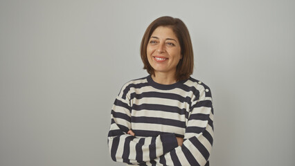 A smiling middle-aged hispanic woman with crossed arms wears a striped shirt against an isolated white background.